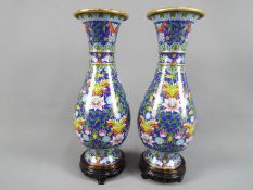 A pair of Chinese cloisonné baluster form vases with elongated neck decorated with scrolling