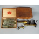 A boxed, vintage brass microscope and a large quantity of slides.