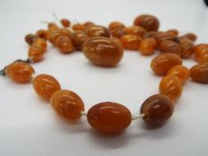 An amber bead necklace (in need of re-stringing), largest bead 30 mm x 20 mm,