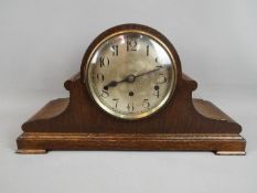 An oak cased Napoleons hat-styled mantel clock, silvered dial with Arabic numerals,