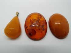 Two oval amber cabochons, largest 4 cm x 3 cm and a teardrop pendant 17 grams all in.