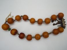 A butterscotch amber bead necklace with sixteen rounded beads, largest bead approximately 2.