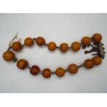 A butterscotch amber bead necklace with sixteen rounded beads, largest bead approximately 2.