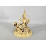 A 19th century gilt bronze figure depicting Manjushri / Shiva seated on a lion,