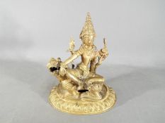 A 19th century gilt bronze figure depicting Manjushri / Shiva seated on a lion,