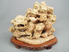 A large highly detailed Chinese soapstone carving depicting an adult Guardian Lion with eight