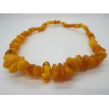 A graduated amber bead necklace, largest bead 25 mm x 13 mm, smallest 10 mm x 7 mm,