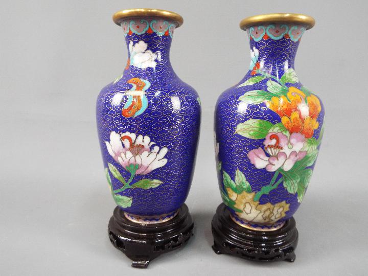 A small pair of Chinese cloisonné vases decorated with flowers and butterfly against a blue ground,