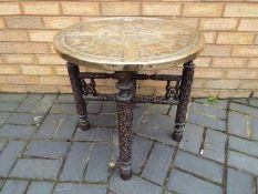 A Benares brass tray table on folding support,