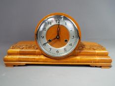 An Art Deco styled mahogany case mantel clock, the case with inlay and carved decoration,