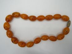 A strand of 18 oblong amber beads, each approximately 25 mm x 16 mm and 46 cm total length,