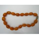 A strand of 18 oblong amber beads, each approximately 25 mm x 16 mm and 46 cm total length,