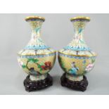A pair of Chinese cloisonné vases decorated with flowers, birds and insects on an ivory ground,
