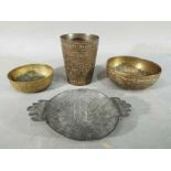 Four middle eastern metal dishes, comprising four bowls and a cup having chased decoration.