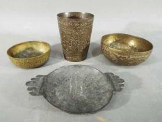 Four middle eastern metal dishes, comprising four bowls and a cup having chased decoration.