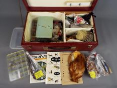 A wooden box containing a small collection of ready made fishing flies together with a large