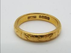 A 22ct gold hallmarked wedding band with chased decoration, size N, approximately 5.35 grams all in.