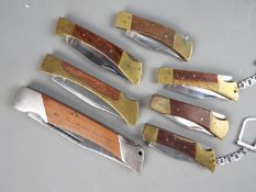 Seven folding knives of varying size.