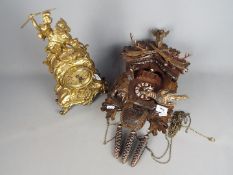 A cuckoo clock with carved decoration and three 'pinecone' weights and a brass cased mantel clock