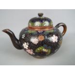 A small cloisonné teapot with floral decoration on a black ground, approximately 10.5 cm (h).