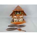 A black forest cuckoo clock with three weights and pendulum.
