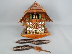 A black forest cuckoo clock with three weights and pendulum.