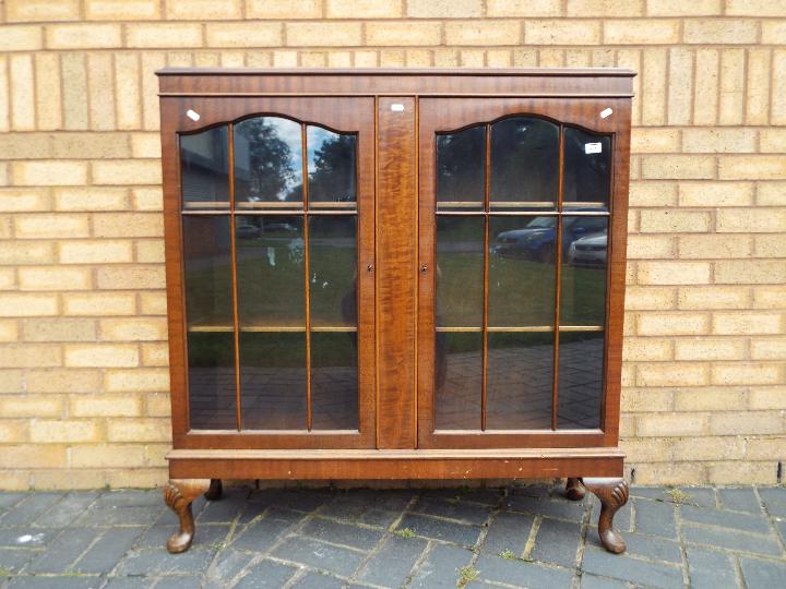 A twin door display cabinet raised on four supports, having two internal shelves,