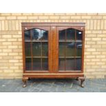 A twin door display cabinet raised on four supports, having two internal shelves,