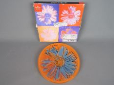 An Andy Warhol 'Daisies' plate for Rosenthal, orange ground, in original box. Approximately 19.