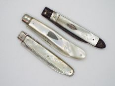 Three folding fruit knives, one white metal bladed example with vacant cartouche to the handle,