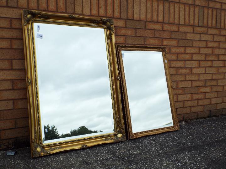 Two decorative gilt framed wall mirrors, largest approximately 76 cm x 106 cm.