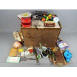 A wooden fishing box containing a good selection of hooks, weights, line, floats, spinners, reels,