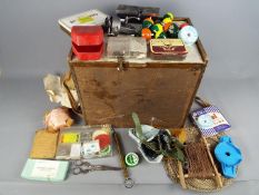 A wooden fishing box containing a good selection of hooks, weights, line, floats, spinners, reels,