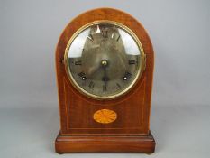 An arch top mantel clock with inlaid decoration, Roman numerals to a silvered dial, with pendulum,