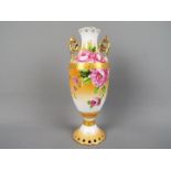 A mid-century twin handled vase decorated with roses against a peach ground,