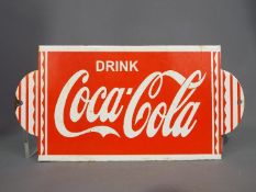 An enamelled sign advertising Coca Cola,