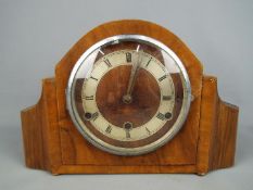 A wood cased mantel clock with Roman numeral chapter ring,