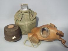 A gas mask with canister and War Department issued field canteen and pouch.