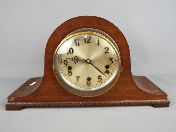 A Napoleons hat mantel clock with carved detailing, Arabic numerals to the dial, with pendulum.