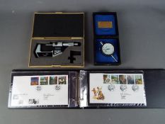 An album containing a collection of first day covers, boxed Mitutoyo measuring gauge and similar.