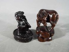 A vintage Japanese dark wood Netsuke depicting a lady bathing,