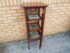 An Edwardian cuboid display cabinet, glazed on all sides with shelved interior on tapering supports,