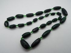 A graduated Malachite green hard stone necklace separated by small glass beads,