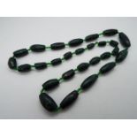 A graduated Malachite green hard stone necklace separated by small glass beads,