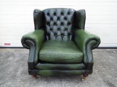 A green leather Chesterfield armchair.