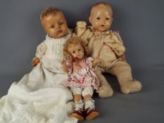 A collection of three composition dolls to include a boy baby doll with jointed head,