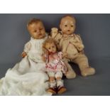 A collection of three composition dolls to include a boy baby doll with jointed head,