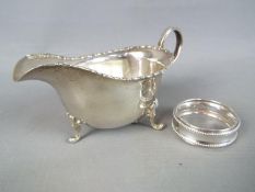 A George V hallmarked silver sauce boat, Birmingham assay 1915 and a hallmarked silver napkin ring,