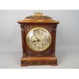 A highly carved wooden mantle clock with pendulum,