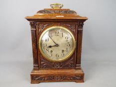 A highly carved wooden mantle clock with pendulum,